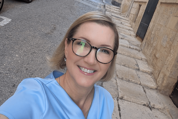 pretty blonde woman with glasses in a blue blouse.