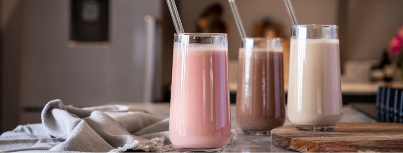 Three glasses of Eve Meal Replacement Shakes with straws on a wooden board.