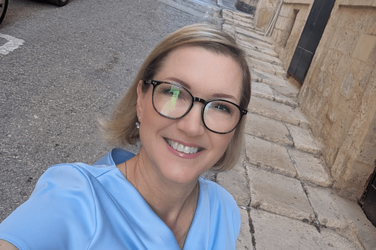 pretty blonde woman with glasses in a blue blouse.