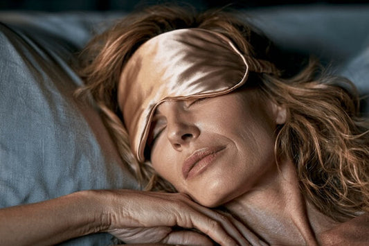 Woman in bed, eyes closed,  sleep mask pushed up forehead