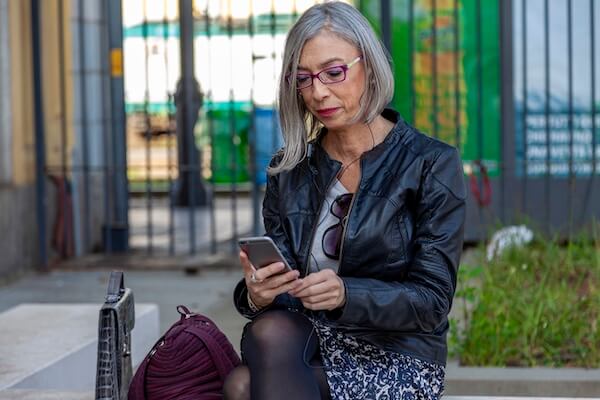Woman over 40 sitting on a bench looking at her phone