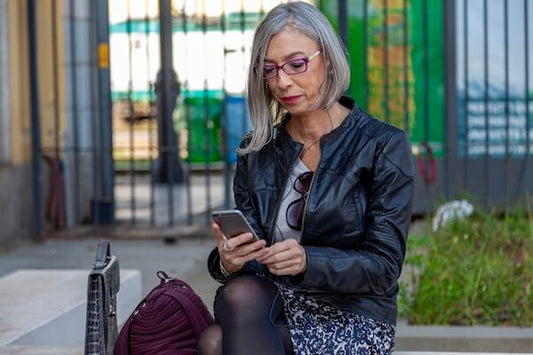 Woman over 40 sitting on a bench looking at her phone