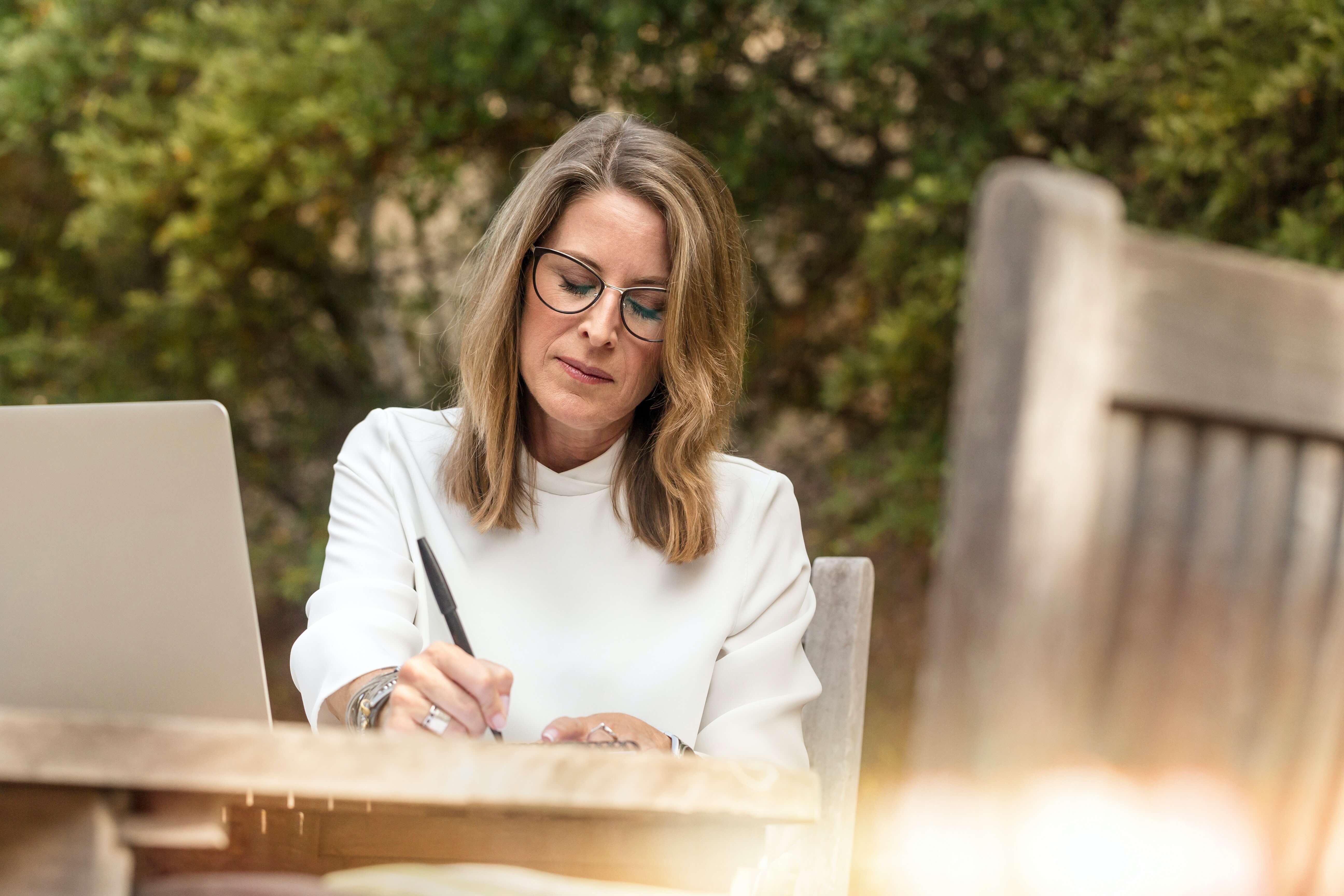 Middle aged woman working on laptop outdoors