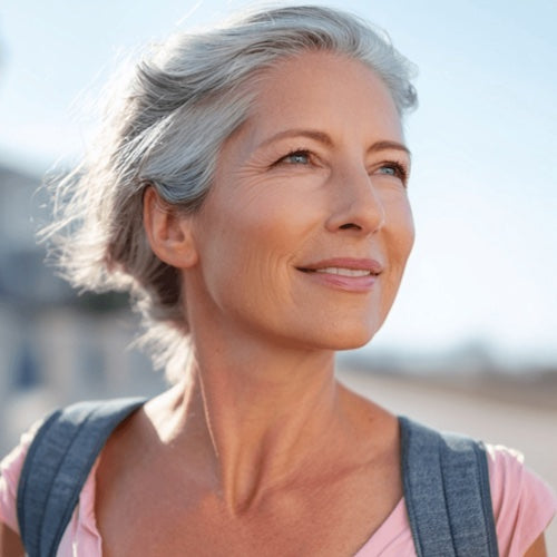 Woman with gray hair smiling outdoors on a clear day
