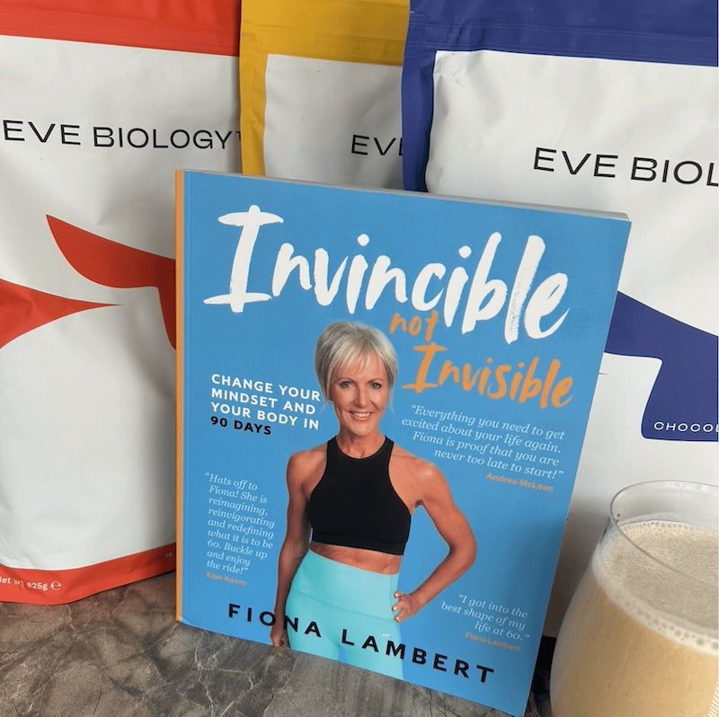 Book titled 'Invincible Not Invisible' by Fiona Lambert with colorful bags in the background.