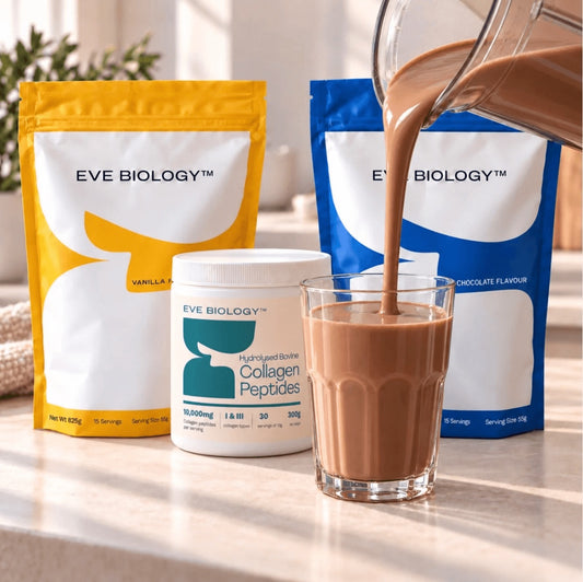 Three bags of Eve Biology supplements and a glass of chocolate-flavored  meal replacement shake on a kitchen counter, with more being poured into the glass.