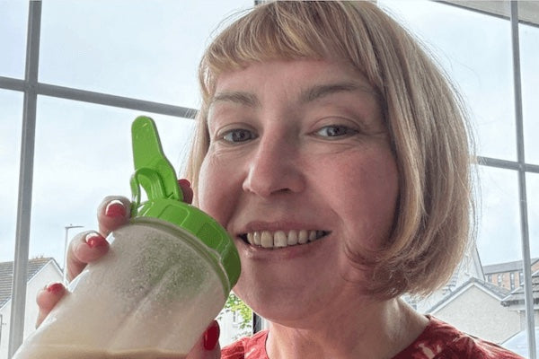 woman holding a shaker with a green cap indoors
