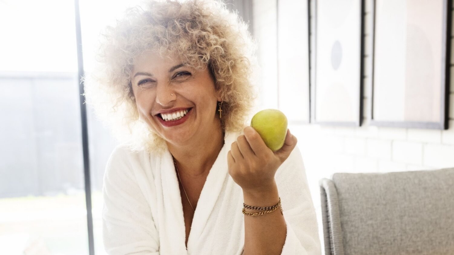 Woman holding a green apple indoors