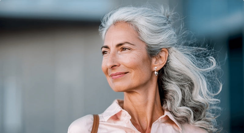 Woman with gray hair smiling outdoors