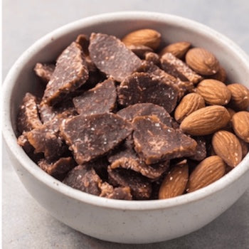 Bowl of beef jerky,  almonds on a light gray background