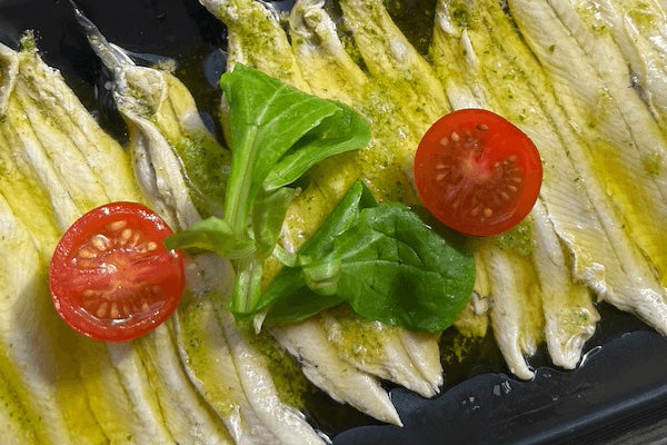 Fried zucchini slices with pesto and cherry tomatoes on a black plate
