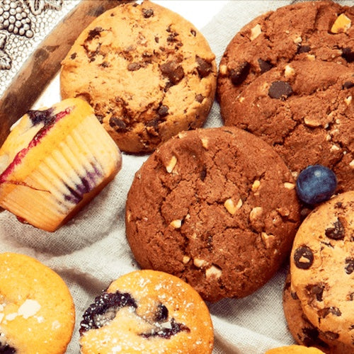 Assorted cookies including chocolate chip, oatmeal, and blueberry on a textured surface.