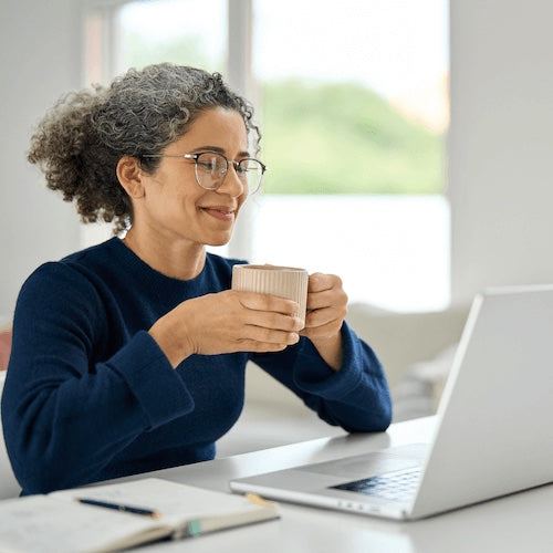 Woman holding a coffee watching an online meeting
