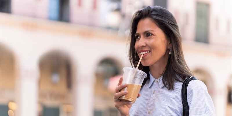 Woman exploring city drinking iced coffee