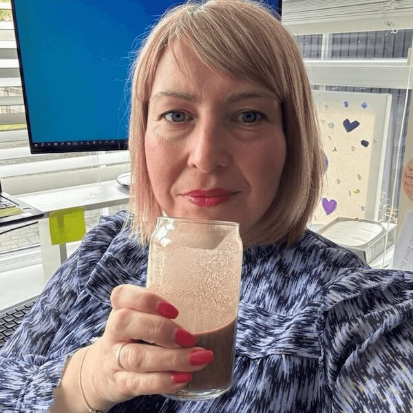 Woman holding a glass of a layered drink in an office setting