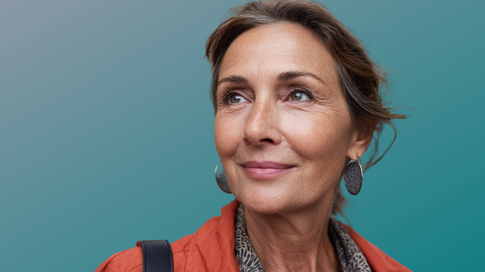 Woman with a warm smile against a teal background