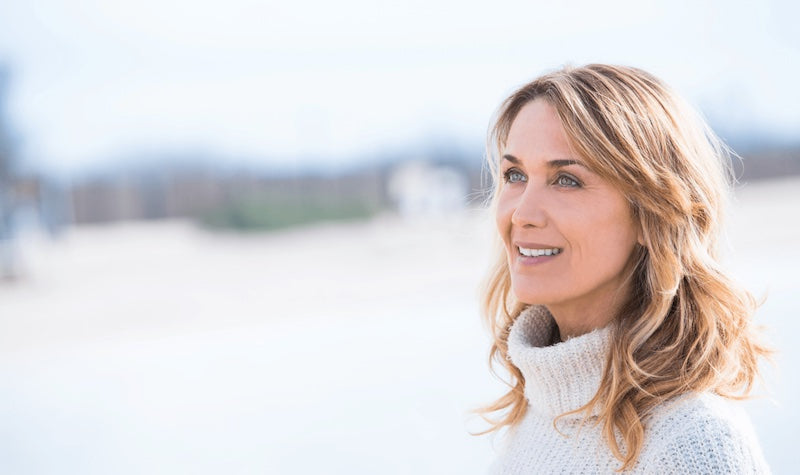 Woman with blonde hair wearing a white sweater outdoors