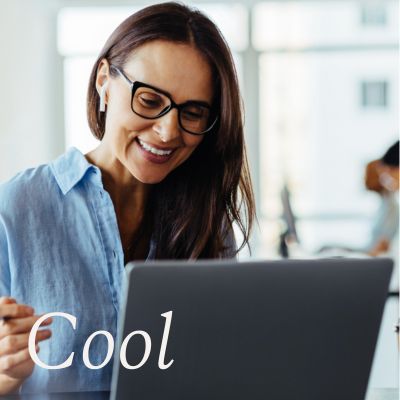 Woman sitting at a laptop, blue shirt, glasses