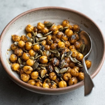 Bowl of roasted chickpeas with pumpkin seeds on a light background