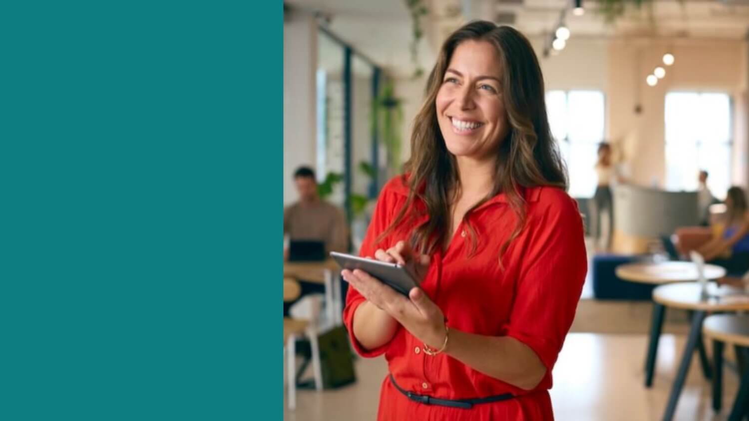 Woman in a red shirt holding a tablet in an office setting