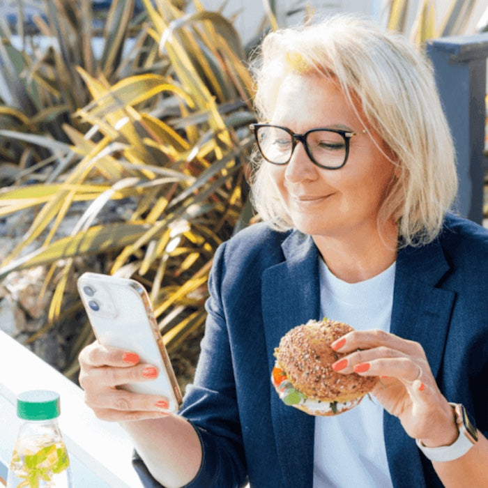 Woman eating a sandwich while scrolling
