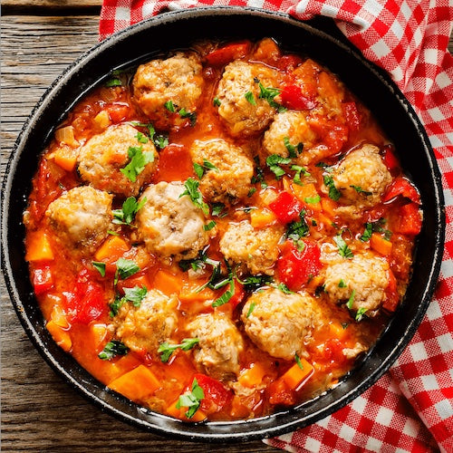 Bowl of meatballs  with vegetables on a checkered tablecloth