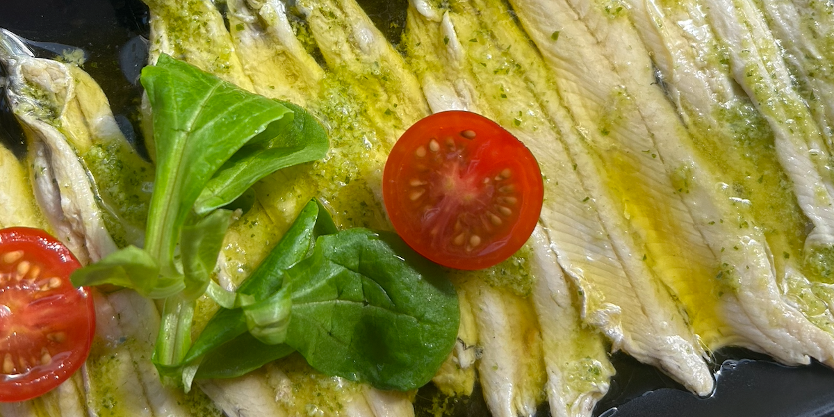 Fish fillets with pesto, tomatoes, and basil on a plate