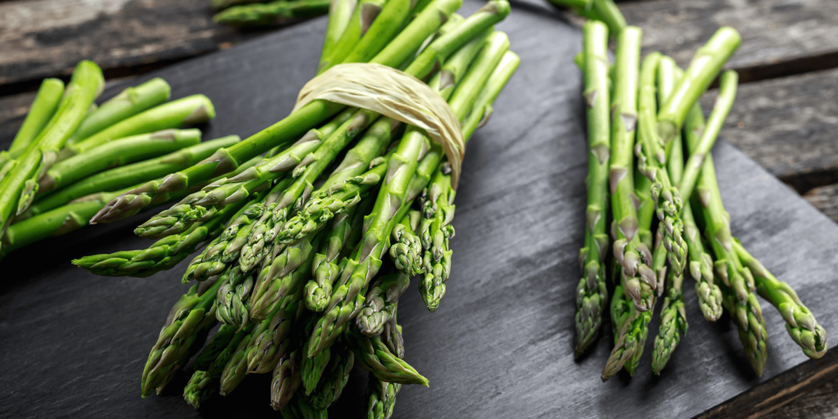 Bundles of green asparagus on a dark slate surface
