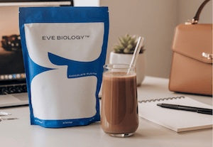 Meal replacement shake on a desk, handbag in background.

