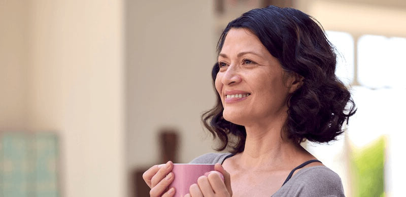 Woman smiling with cup of tea, morning light