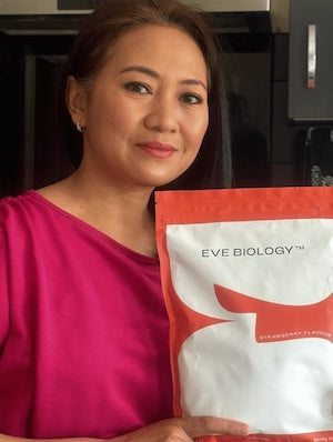 Woman holding a red and white package labeled 'EVE BIOLOGY' in an indoor setting.