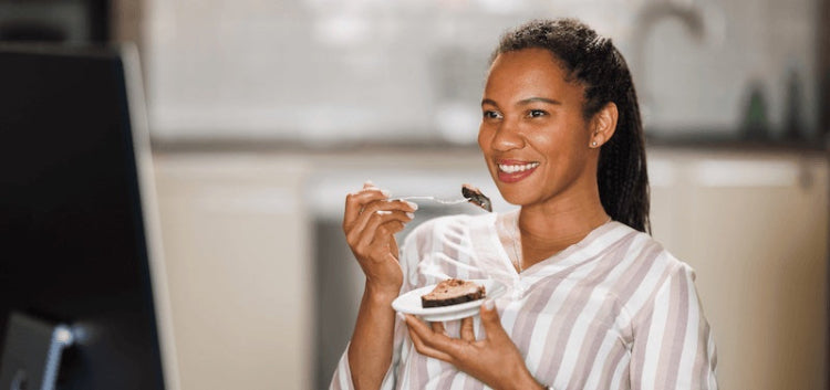 Woman eating a piece of cake at work