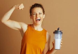 Woman holding a protein shake flexing her bicep