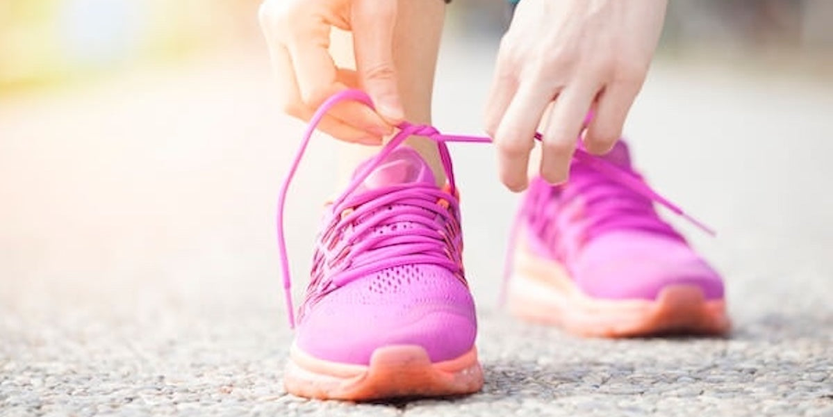 Person tying pink running shoes on a blurred background