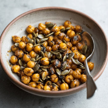 Bowl of roasted chickpeas with pumpkin seeds on a light background