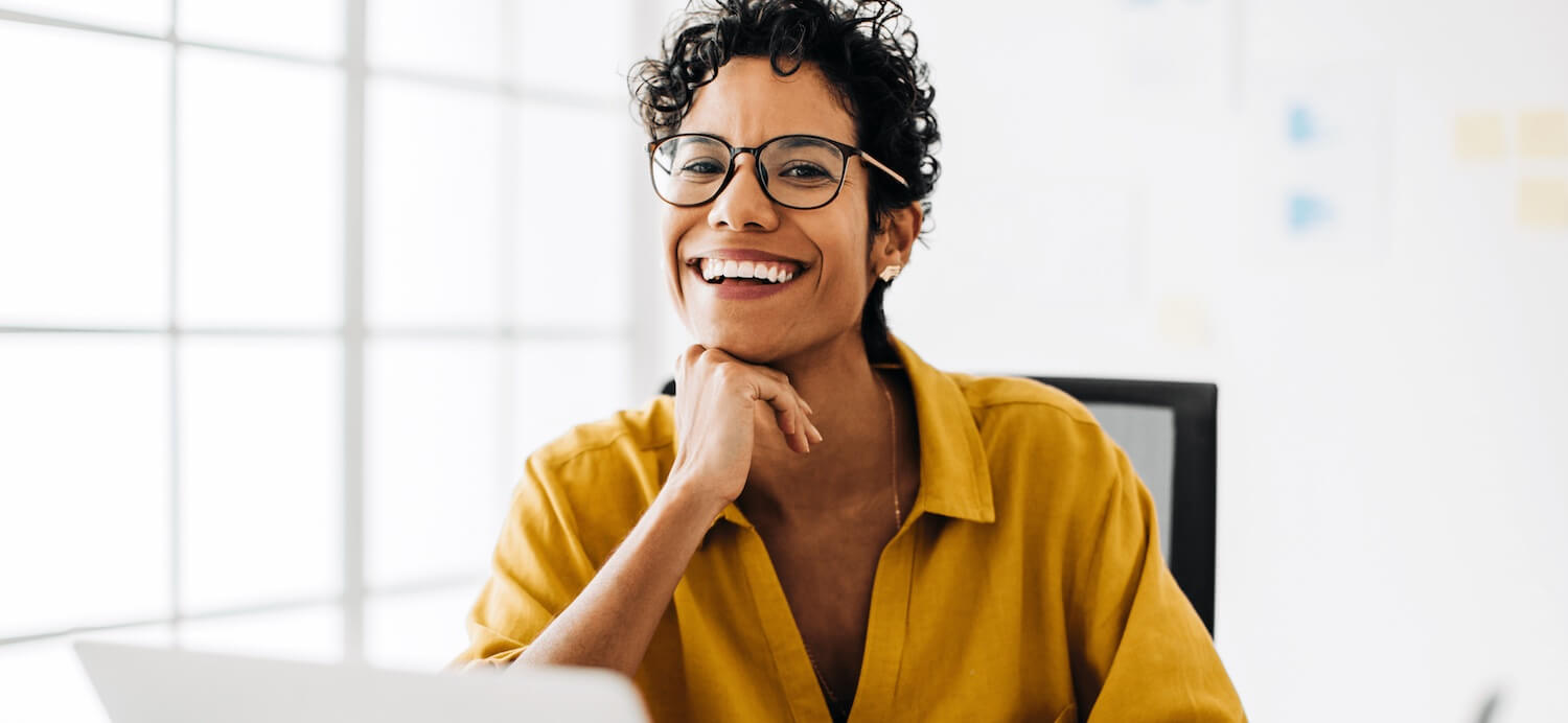 Woman in a yellow shirt smiling in an office setting