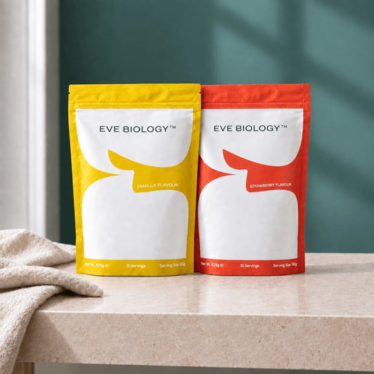 Two stand-up pouches of Eve Biology supplement powder on a light stone countertop. The left pouch is yellow with vanilla flavour text and the right pouch is red-orange with strawberry flavour text.