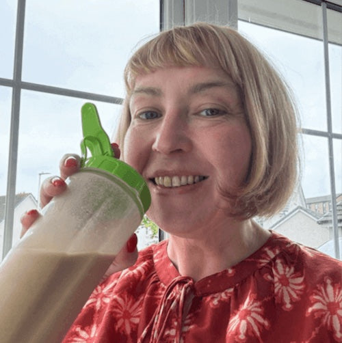 Person holding a shaker with a green cap indoors